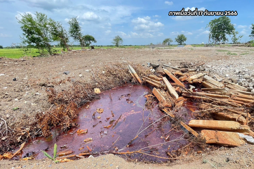 บ่อน้ำขนาดเล็ก ที่มีคราบสีส้มเกาะเศษไม้ เศษโฟม ขวดพลาสติก และเศษซากสิ่งก่อสร้างบริเวณขอบบ่อ อีกทั้งมีกองดินบริเวณรอบบ่อ