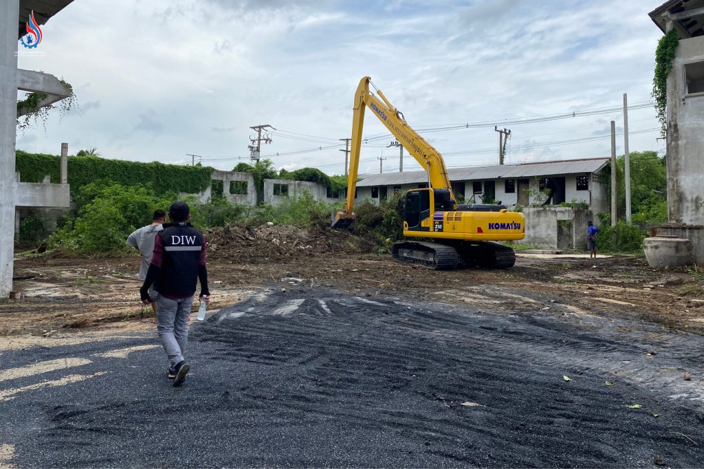 นำรถแบ็คโฮมาดำเนินการถางตัดต้นไม้และวัชพืชหน้าอาคารหมายเลข 1